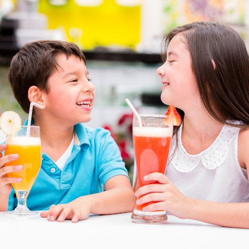 Two children with brightly colored drinks at a table