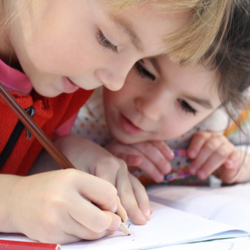 Two little girls working on a paper